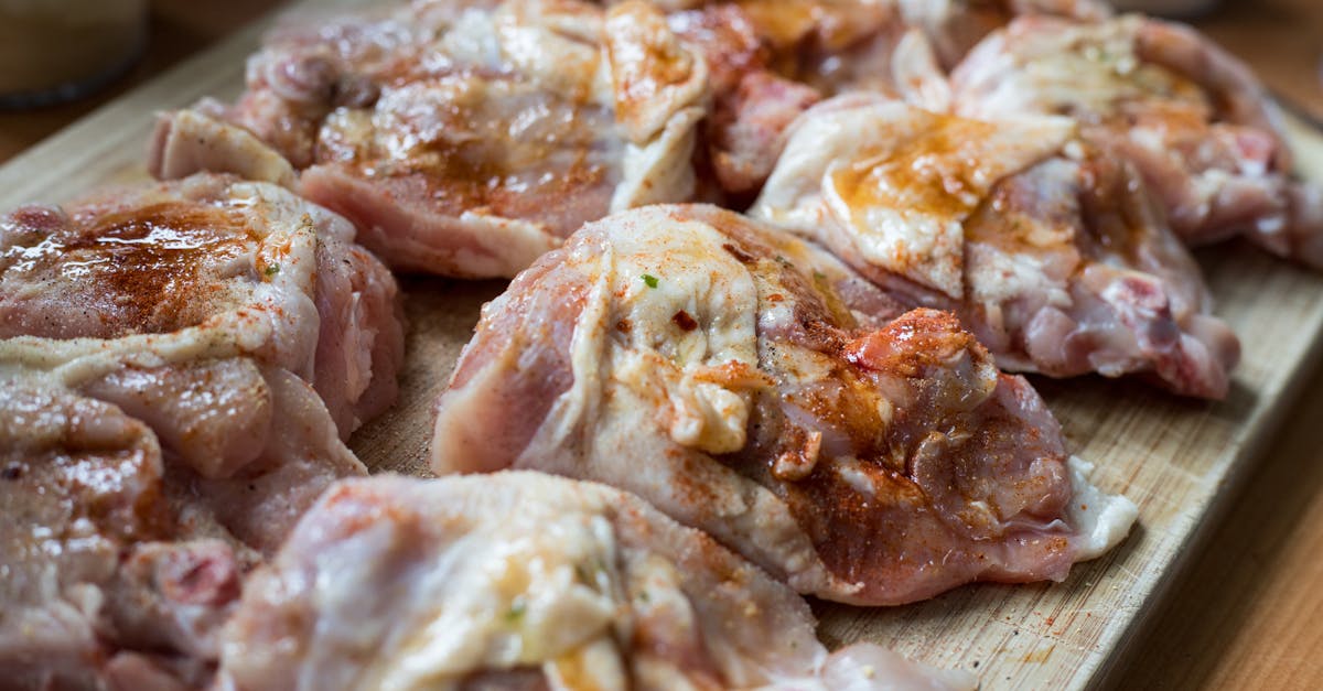 Raw chicken pieces seasoned with spices on a wooden board, ready for cooking